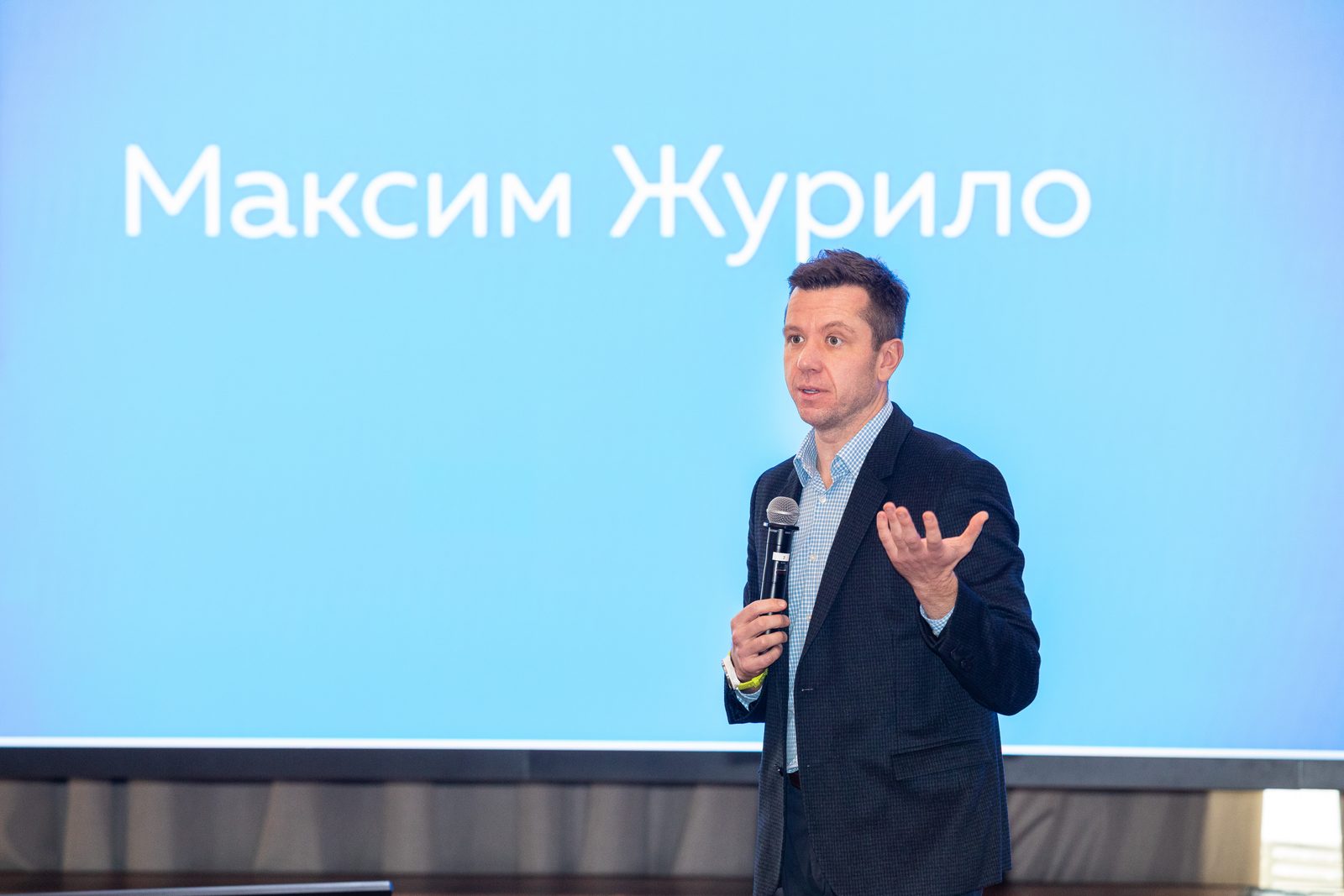 Максим с микрофоном на сцене, на экране за ним его имя