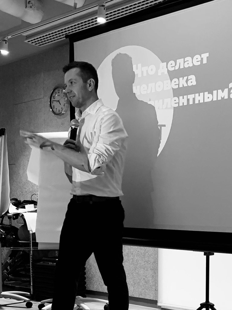 Чёрно-белое фото: Максим выступает на фоне слайда